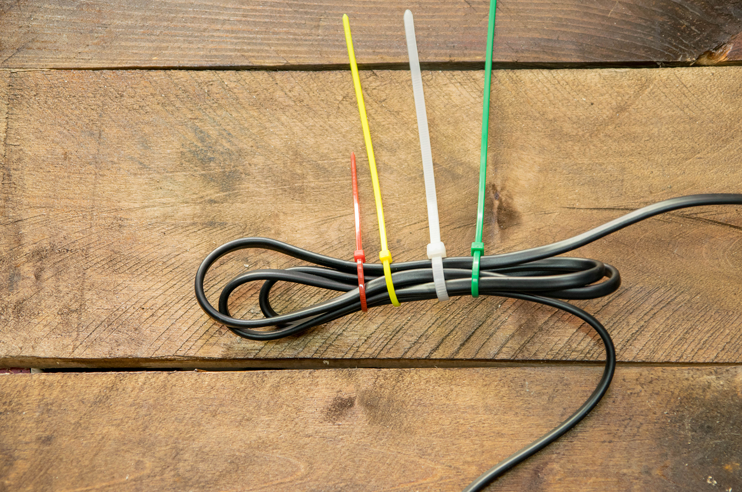 Black cables tied up with four different colored zip ties.